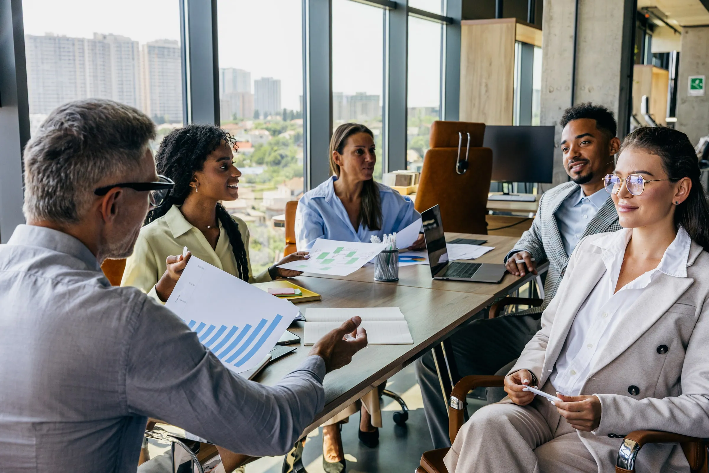 A diverse group of executives reviewing charts together at a conference table